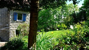 A stone building with blue shutters, surrounded by lush greenery and a well-maintained lawn. - Apartment 'altes forsthaus schotten' with Shared Garden, Balcony and Wi-Fi (Schotten)