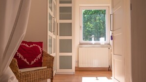 A hallway with a wicker chair, a radiator, and a window with a view of trees. - Apartment 'altes forsthaus schotten' with Shared Garden, Balcony and Wi-Fi (Schotten)