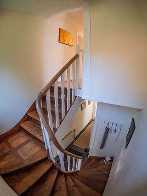 A wooden staircase with white railings, leading to an upper floor.