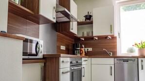 A modern kitchen with built-in appliances, wooden accents, and a window with a view. - Apartment 'altes forsthaus schotten' with Shared Garden, Balcony and Wi-Fi (Schotten)