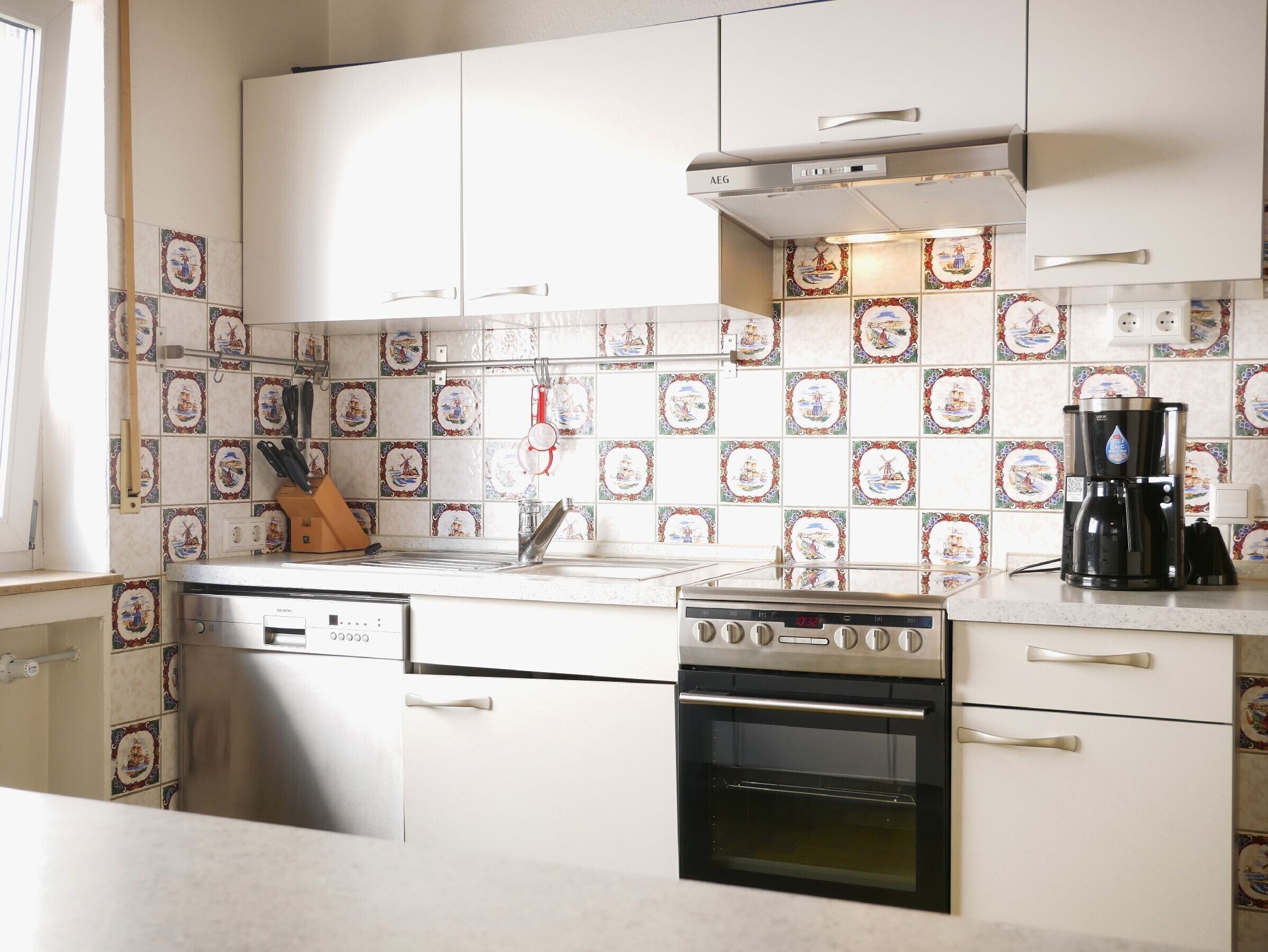 A kitchen with white cabinets, a stainless steel dishwasher, an oven, and a coffee maker.