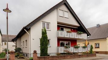 Ein zweistöckiges Wohnhaus mit Balkon, kleinem Garten und einer Straßenlaterne.