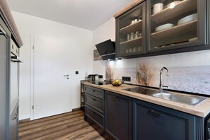 A modern kitchen with dark cabinetry, a wooden countertop, a built-in sink, and a microwave.