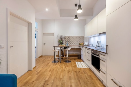 A modern kitchen with white cabinets, a wooden floor, and a bar area with stools.. Apartment 'Ferienwohnung Black Forest' with Wi-Fi