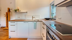 A modern kitchen with white cabinetry, a stainless steel sink, and a built-in oven.