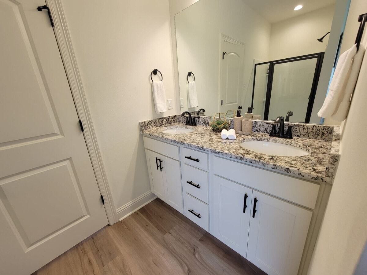 Une salle de bain avec un double lavabo, des meubles blancs et un grand miroir.