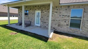 Un immeuble résidentiel doté d’un porche couvert, d’une façade en briques et d’un petit jardin à l’avant.