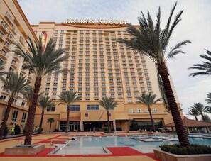 Ein Hotel mit einem großen Gebäude, mehreren Balkonen und einem Poolbereich.