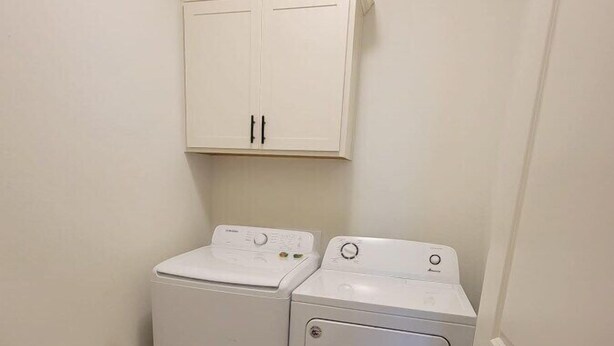 Une buanderie équipée de deux machines à laver et deux sèche-linge superposés, avec un meuble blanc au-dessus et un plancher en bois.