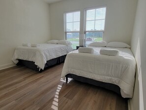 Ein Hotelzimmer mit zwei Betten, Holzboden und einem Fenster mit Jalousien.