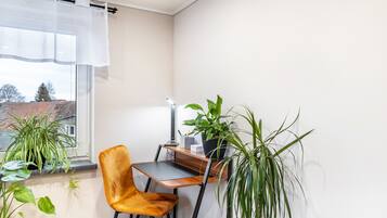 Una habitación pequeña con escritorio, silla y plantas en macetas.