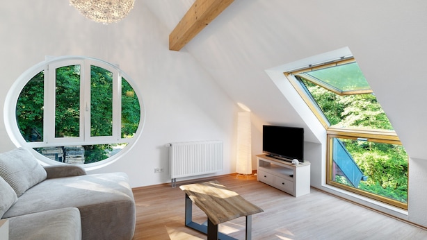 Ein modernes Schlafzimmer im Loft-Stil mit Dachfenster, rundem Fenster, Fernseher und einer Holzbank.