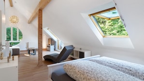 Ein modernes Schlafzimmer im Loft-Stil mit Dachfenster, einem Bett, einem Schreibtisch und einem Stuhl.