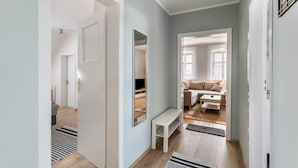 A hallway with a bench, a mirror, and a door leading to a living area with a sofa and a coffee table.