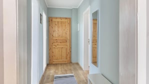 A hallway with wooden doors, a radiator, and a mirror on the wall.