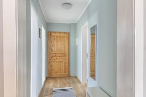 Ein Flur mit Holztüren, einem Heizkörper und einem Spiegel an der Wand.
