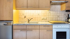 A kitchen with wooden cabinets, a built-in oven, a dishwasher, and a tiled backsplash.