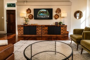 A reception area with a wooden reception desk, a framed sign, a round mirror, and a green armchair.