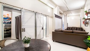 A modern living room with a sofa, a dining table with a plant, and a sliding door closet. - Downtown Loft w/Parking, Fitness & Movie room (Knoxvile)