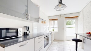 Una cocina moderna con microondas, cafetera y lavamanos.
