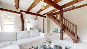 Un salón amplio con un sofá blanco, una mesa de centro de cristal y una escalera de madera.