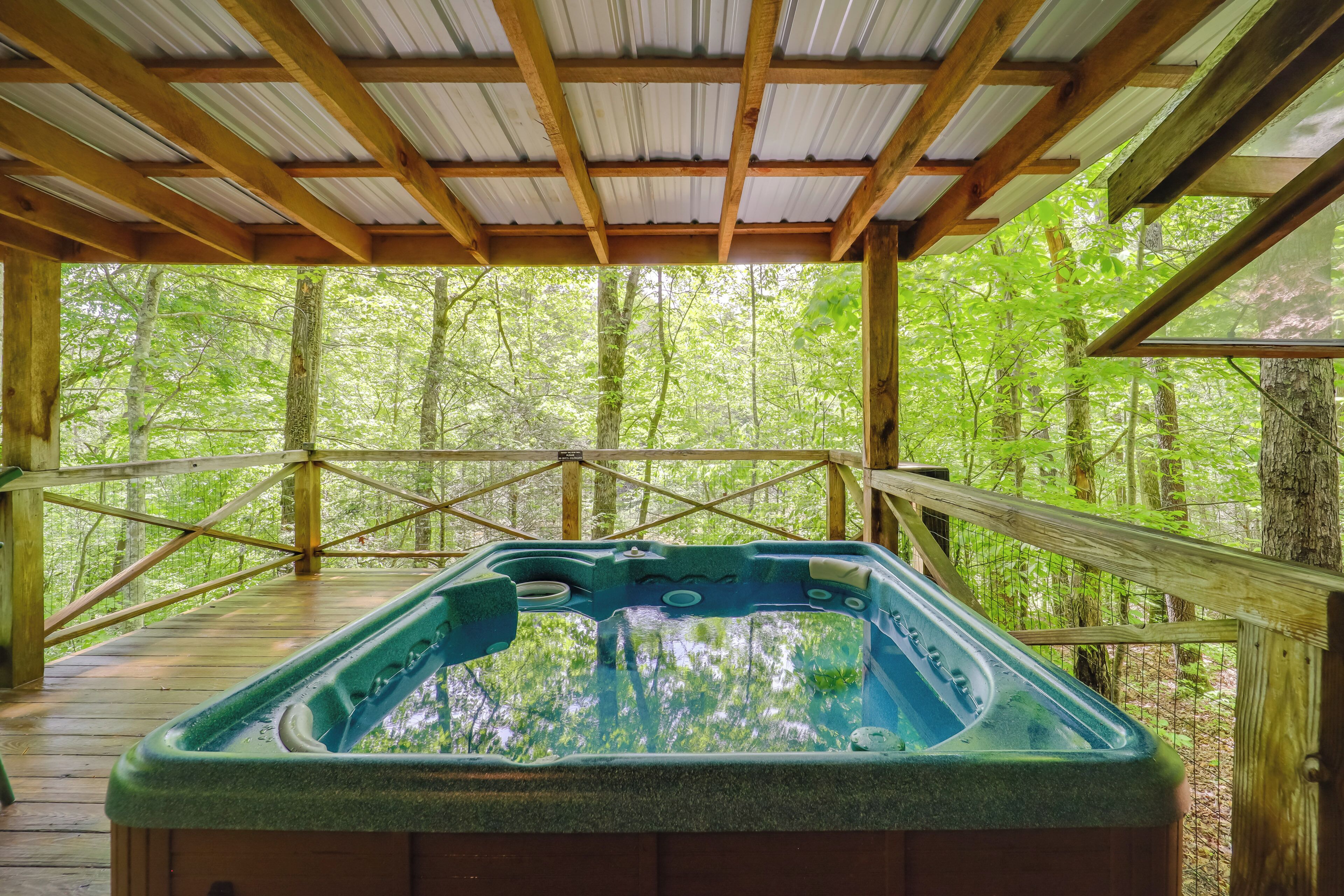 A hot tub in a wooden deck with a metal roof, surrounded by a forest.