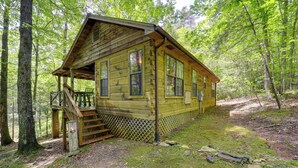 Eine Holzhütte mit einer Veranda und einer Treppe, umgeben von Bäumen.