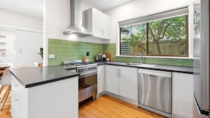 A modern kitchen with white cabinets, a stainless steel range, and a dishwasher.
