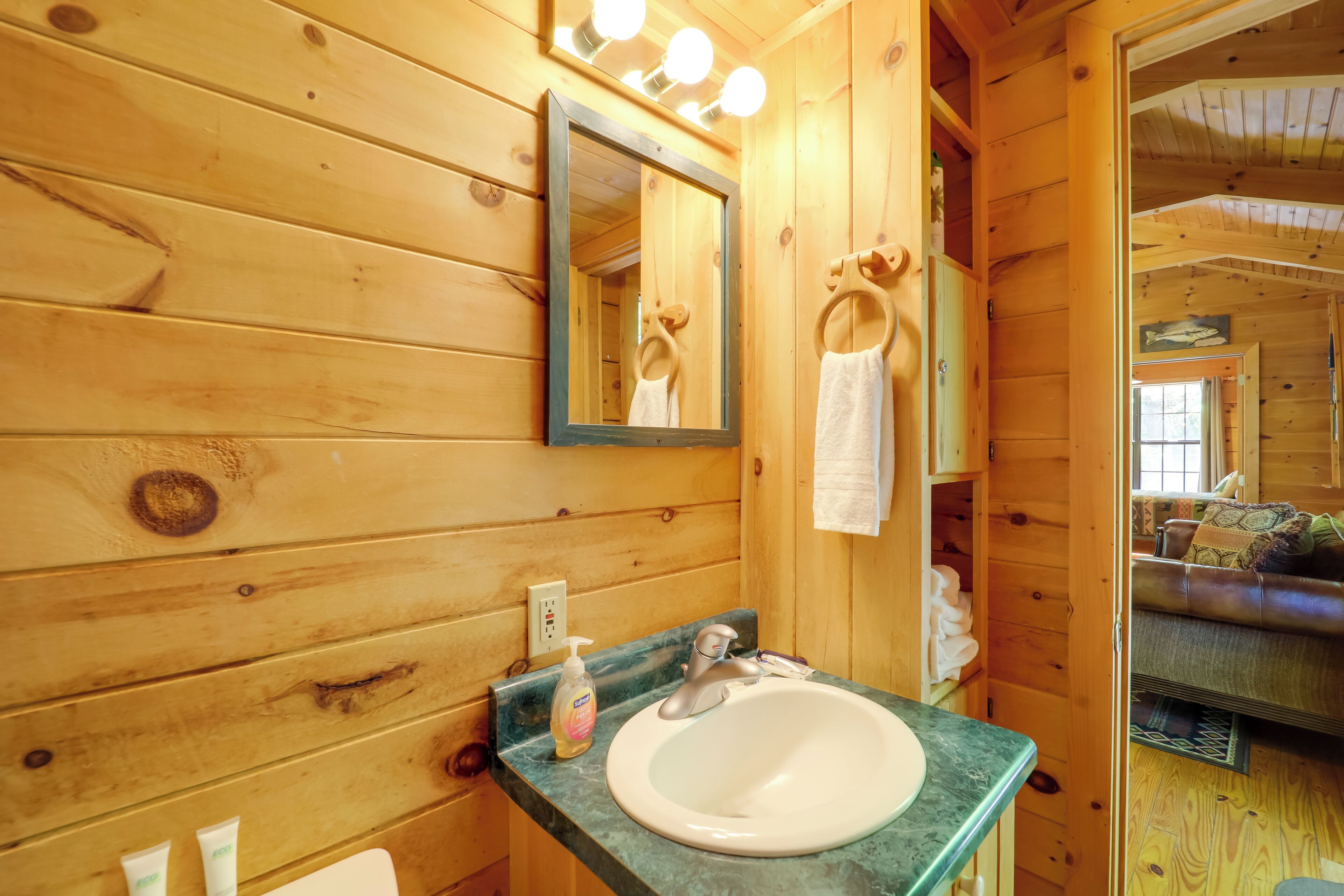 A wooden cabin bathroom with a sink, mirror, and towel rack.