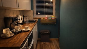 A compact kitchen with a coffee machine, cups, and a small trash bin. - Cambridge Garden Studio                  Private Entrance & Free Parking (Cambridge)