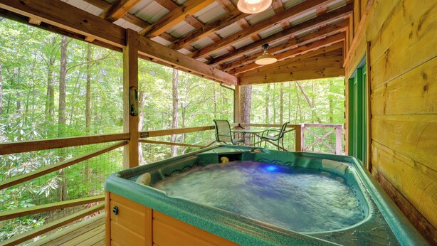 Eine Holzhütte mit Whirlpool, einer Holzdiehne und Blick auf den Wald.