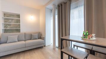 Una sala moderna con un sofá gris, una mesa de comedor con bancos y un mueble de pared.