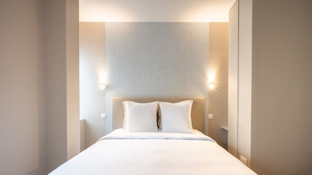 Une chambre d’hôtel bien aménagée, avec un grand lit, deux lampes de chevet et un mur à motifs derrière le lit.