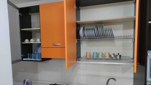 Una cocina con un armario abierto color naranja, una estufa a gas, un fregadero y escurreplatos.