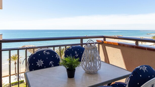 A balcony with a table, chairs, and a potted plant.