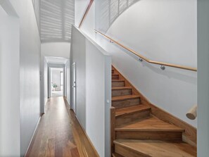 A modern interior with a wooden staircase, a hallway, and a door leading to another room. - Bickley s Place A Luxury Retreat on the Golf green (Dunsborough)