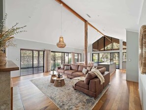 A spacious living area with a large sofa, a coffee table, and a hanging light fixture. - Bickley s Place A Luxury Retreat on the Golf green (Dunsborough)