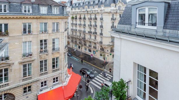 A multi-story building with balconies, a street view, and a pedestrian crossing.