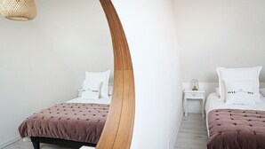 Et soveværelse med to senge, hver med en hvid pude og et natbord med en lampe.