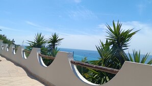 A tiled walkway with a curved railing, overlooking a body of water. - Residenza Stefanelli (Torre Marino, Capo Vaticano)