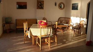 Ein Essbereich mit Tisch und Stühlen, einer Couch und einem Fernseher auf einem Beistelltisch.