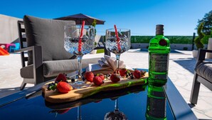 A table with two glasses of a clear beverage, a bottle of London Dry Gin, and a wooden board with strawberries and blueberries. - Stunning apartment in Tinj (Tinj)