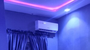 Een slaapkamer met een bed, gordijnen, een airconditioning en een betegelde vloer.