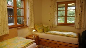 Une petite chambre confortable avec deux lits simples, une table de chevet et une fenêtre avec des rideaux.