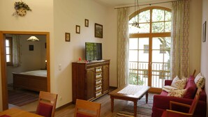 Un salon avec un meuble en bois, un téléviseur, un canapé rouge et une fenêtre avec des rideaux.