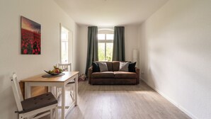 Ein Zimmer mit einem Holzespeisetisch, einem weißen Stuhl, einem braunen Sofa und einem Bild an der Wand.
