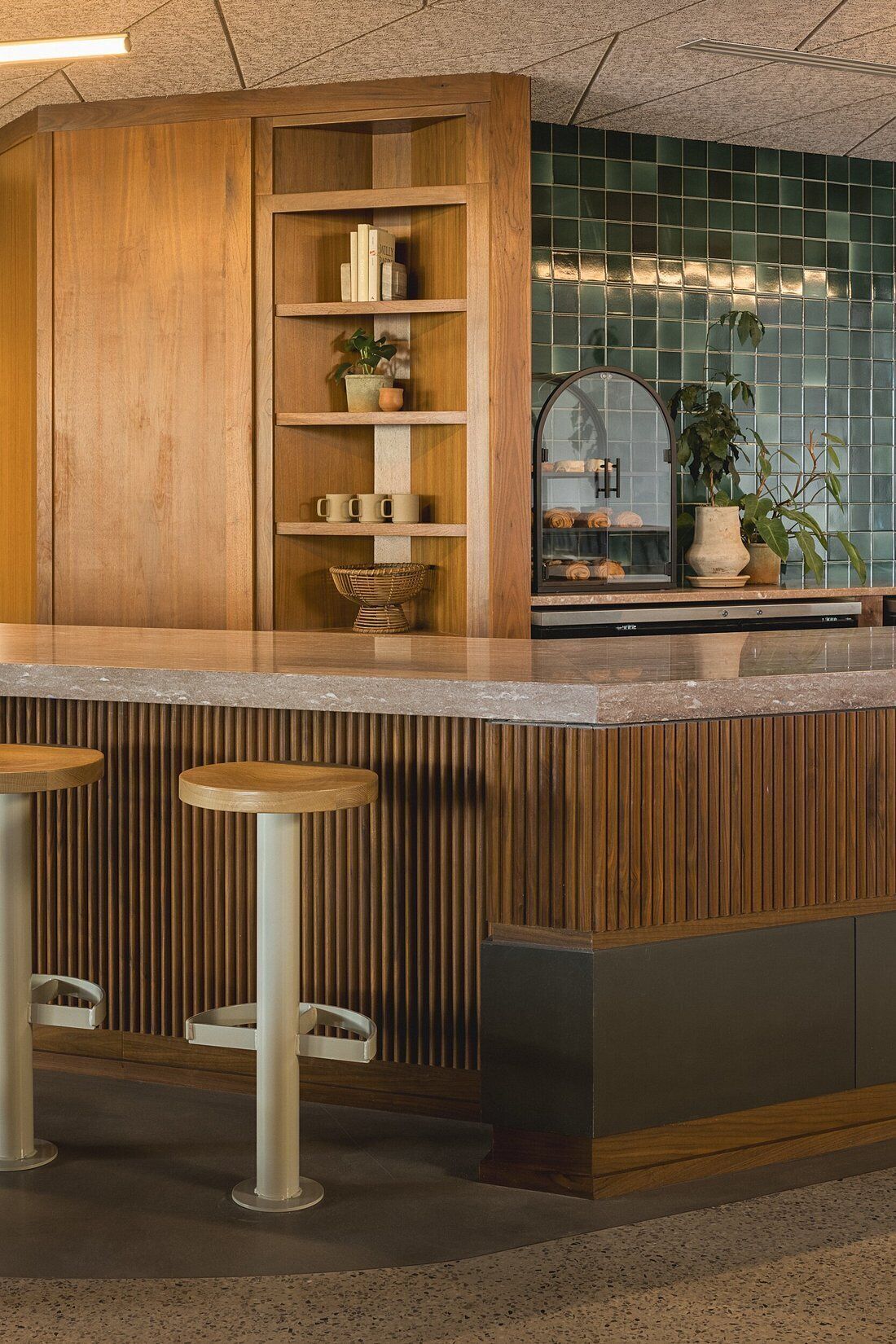 A kitchen with wooden cabinetry, a tiled backsplash, and two bar stools.