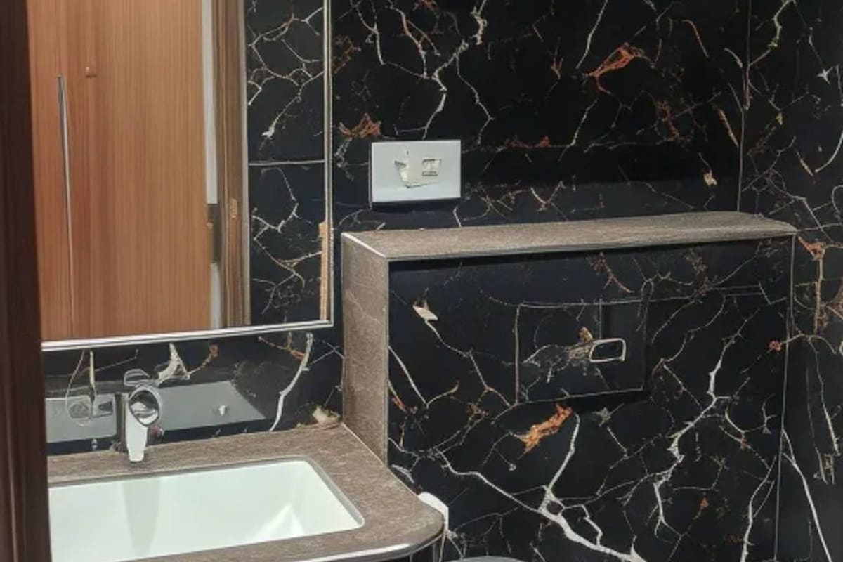 Un baño con lavamanos de mármol, un espejo y una puerta de madera.