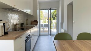A modern kitchen with white cabinets, a wooden countertop, and a built-in oven. There is a sliding glass door leading to an outdoor patio area.