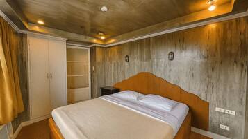 A bedroom with a wooden headboard, a bed with white linens, a nightstand, and a wardrobe with a mirror.